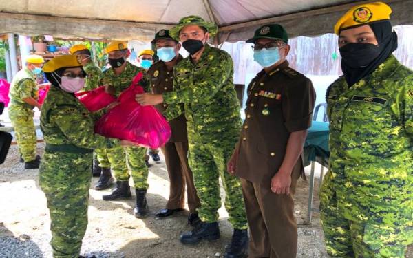 Asiah, (dua dari kiri) menerima bantuan makanan yang disampaikan oleh Mior Muhammad Taufik (tiga dari kanan). - Foto Sinar Harian.