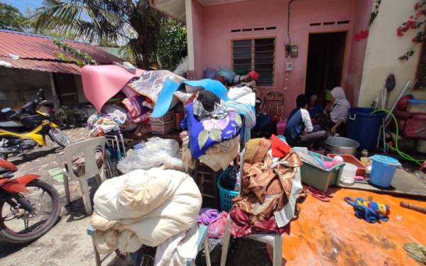 Longgokan barangan rosak akibat banjir pada Isnin di depan rumah Muhd Ridhuwan di Kampung Kuala Sungai Baru.