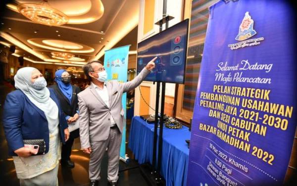 Datuk Bandar Petaling Jaya, Mohamad Azhan Md Amir (kanan) menunjukkan sistem ‘headcount’ yang menggunapakai fungsi infra merah untuk mengawal jumlah pengunjung di bazar Ramadan ketika Majlis Pelancaran Pelan Strategik Pembangunan Usahawan Petaling Jaya 2021-2030 dan Sesi Cabutan Bertuah Undi Petak Bazar Ramadan 2022 di Dewan Sivik MBPJ, pada Khamis.Foto FB MBPJ.