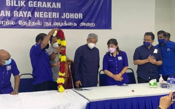 Ahmad Zahid (tengah) ketika cuba dipakaikan bunga rampai oleh wakil MIC selepas lawatannya di Bilik Gerakan MIC Johor di Tampoi pada Jumaat.