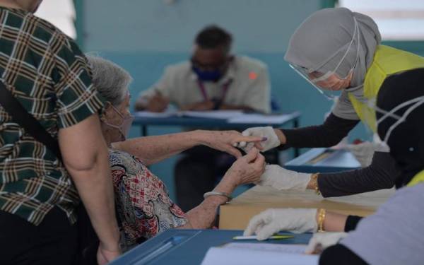 Seorang petugas membantu warga emas mencelup jari ketika proses mengundi bagi Dewan Undangan Negeri Larkin pada PRN Johor di Pusat Mengundi Sekolah Kebangsaan 1 Larkin hari ini. - Foto Bernama