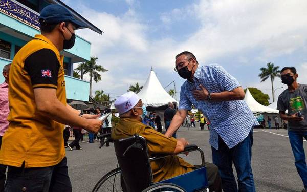 Hishammuddin beramah mesra bersama pengundi ketika tiba di Pusat Mengundi Sekolah Agama Taman Sri Lambak untuk mengundi sempena PRN Johor pada Sabtu.