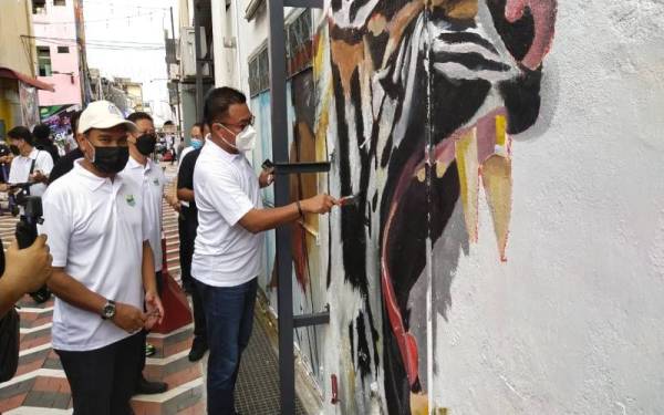 Mohd Sharkar memberikan sentuhan kreatifnya pada mural karya pelukis tempatan di Kuantan Art Street di sini pada Ahad.