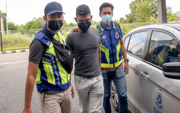 Mohamad Shahzrie (tengah) dikawal polis ketika tiba di pekarangan Mahkamah Sesyen Kota Bharu pada Isnin.