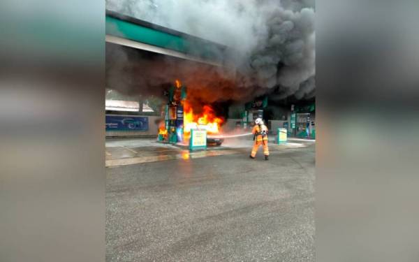 Anggota bomba memadamkan kebakaran kereta jenis Perodua Kancil yang terbakar di sebuah stesen minyak di Rantau Panjang. - Foto ihsan bomba