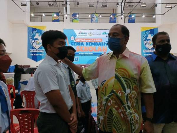 Zambry menyantuni pelajar yang hadir sempena Program Ceria Kembali ke Sekolah #MyAirportCARES di Dewan Merdeka Seri Manjung pada Isnin.