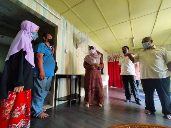 Roziah (tengah) diiringi Ketua Kampung Baru Hicom, Abdul Malik Abdul Rashid (kanan) ketika melawat ke rumah penerima bantuan baik pulih rumah pada Isnin.