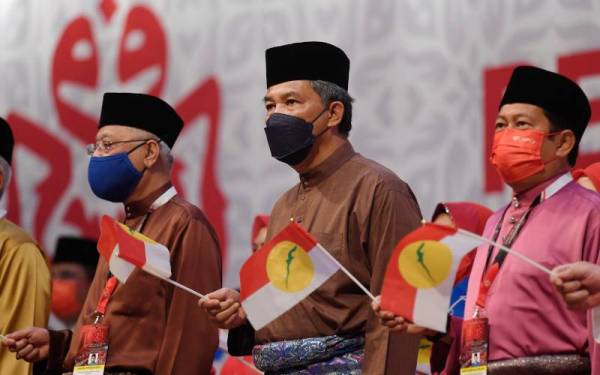 Perdana Menteri yang juga Naib Presiden UMNO, Datuk Seri Ismail Sabri Yaakob (kiri) bersama Mohamad (tengah) melambaikan bendera UMNO ketika menyanyikan lagu ‘Bersatu, Bersedia, Berkhidmat’ pada Majlis Perasmian Perhimpunan Agong Pergerakan Sayap Wanita, Pemuda dan Puteri UMNO sempena Perhimpunan Agung UMNO (PAU) 2021 di Dewan Merdeka Pusat Dagangan Dunia Kuala Lumpur malam ini. Turut sama Setiausaha Agung UMNO, Datuk Seri Ahmad Maslan. - Foto Bernama 