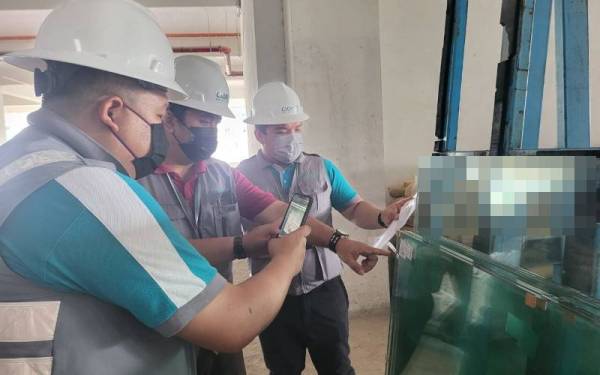 Anggota penguat kuasa CIDB melakukan pemeriksaan dokumen di sebuah tapak pembinaan Cyber City, Kapayan, Penampang pada Khamis.