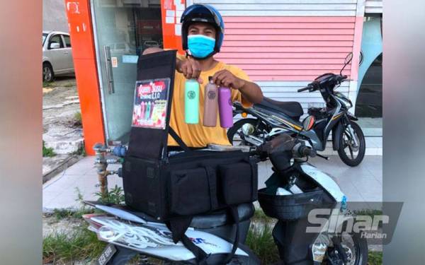 Nik Muhamad Afiq menunjukkan susu berperisa yang dijualnya dengan menggunakan sebuah motosikal di sekitar daerah ini.