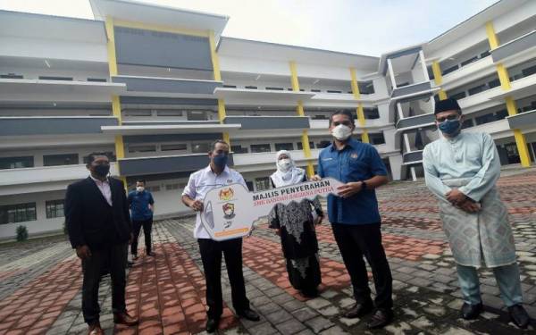 Mohd Radzi (dua dari kanan) menyerahkan replika kunci kepada Penolong Kanan Pentadbir Azman Sharif (dua dari kiri) pada Majlis Penyerahan Sekolah Menengah Kebangsaan (SMK) Bandar Saujana Putra pada Jumaat. - Foto Bernama