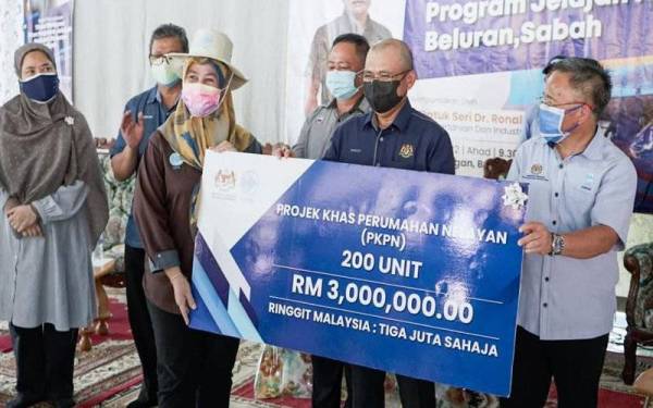 Ronald (dua dari kanan) ketika menyerahkan replika cek peruntukan sebanyak RM3 juta bagi Projek Khas Perumahan Nelayan (PKPN) di Beluran semasa Program Jelajah Nelayan Beluran pada Ahad.