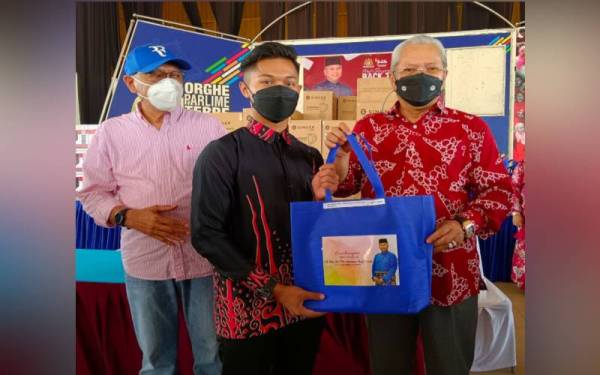 Annuar (kanan) menyampaikan bantuan 'Back To School' kepada pelajar tingkatan enam di Dewan Tun Ghaffar Baba, Kompleks Yayasan Kemiskinan Kelantan (YKK), Kota Bharu, pada Ahad.