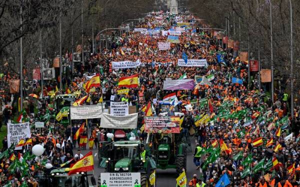 Penunjuk perasaan memegang sepanduk semasa protes di Madrid. - AFP