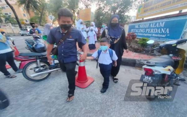 Nuraini (kanan) dan suami, Izzat Ismail menghantar Adam ke sekolah pada hari pertama persekolahan di SK Shah Alam, Seksyen 16.