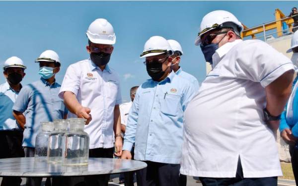 Tuan Ibrahim (dua, kanan) melihat kualiti air yang diproses menerusi Loji Kumbahan Serantau Batu Berendam pada majlis perasmian dan penyerahan loji berkenaan kepada Indah Water Konsortium (IWK) Sdn Bhd di sini, pada Isnin. - Foto Bernama 