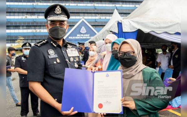 Shafien (kiri) menyampaikan sijil penghargaan kepada Hazelen Liana sempena sambutan Hari Peringatan Polis ke-215 Kontinjen Kelantan di IPK, di Kota Bharu pada Jumaat.