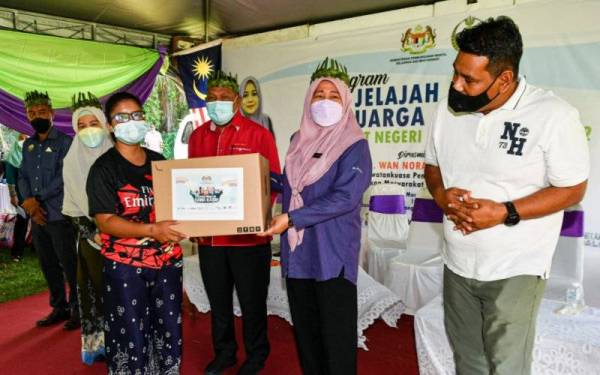 Wan Norashikin (dua,kanan) menyampaikan sumbangan kepada masyarakat Orang Asli, Naseera Cheding pada Program Jelajah Kasih Keluarga Malaysia peringkat negeri 2022 di Padang Sekolah Kebangsaan Suak Padi pada Sabtu. - Foto Bernama 