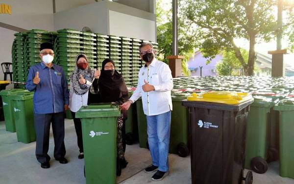 Azizul Kama (kanan) menyerahkan tong sampah beroda kepada penduduk pada Majlis Pelancaran Serahan Tong Fasa Ketiga Kepada Penduduk Zon Meru di Masjid Al-Muttaqin, Jalan Bukit Meru, Taman Meru, di sini pada Sabtu.