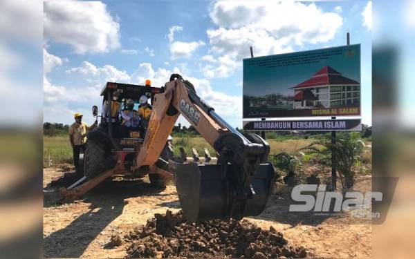 Ahmad (duduk tengah) mengendalikan jengkaut sebagai simbolik kepada perasmian Majlis Pecah Tanah Pembangunan Madinah Al- Salam di Tiong, Kota Bharu, pada Isnin.