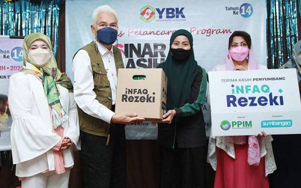 Siti Khadijah (dua dari kanan) menyerahkan sumbangan kotak Infaq Rezeki kepada Zainal Abidin ketika Majlis Pelancaran Sinar Kasih Ramadhan yang diadakan di Yayasan Basmi Kemiskinan.