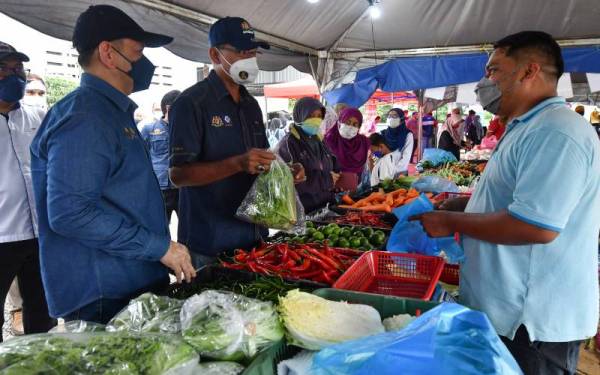 Rosol (dua dari kiri) bertanyakan sesuatu kepada peniaga semasa meninjau Program Jualan Keluarga Malaysia Peringkat Parlimen Hulu Terengganu di Kampung Telaga, Hulu Terengganu pada Sabtu. - Foto Bernama