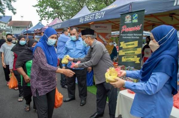 Bakri (tiga dari kiri) ketika membuat edaran dodol kepada pengunjung di Pasar Tani Kuala Pilah.