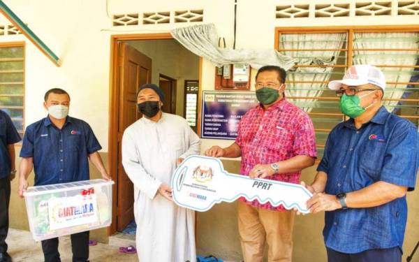 Abdul Rahman (dua dari kanan) menyerahkan kunci rumah kepada penerima di Kampung Peruang, Lipis pada Sabtu. - Foto KPLB