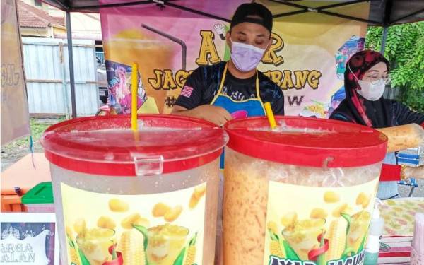 Zulfahmi (kiri) dan isterinya sedang menyediakan air jagung kepada pelanggan di gerai mereka yang mula beroperasi pada jam 4 petang.