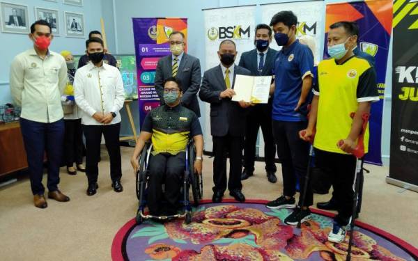 Saarani (tengah) menerima buku ikrar daripada wakil atlet para selepas menyempurnakan Majlis Perasmian Dasar Sukan OKU Perak di Pejabat Menteri Besar Perak, Bangunan Perak Darul Ridzuan di sini pada Rabu.