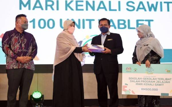 Zuraida (dua, kiri) menyampaikan sumbangan tablet kepada 100 buah sekolah terlibat dalam Program Jelajah Mari Kenali Sawit kepada Pengarah Bahagian Pembangunan Kokurikulum, Kementerian Pendidikan Malaysia, Azman Adnan pada Majlis Pelancaran Perdana Jelajah Mari Kenali Sawit, pada Rabu. Foto Bernama
