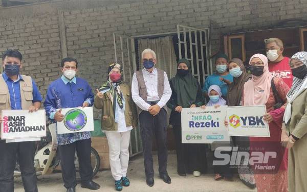 (Tiga dari kiri) Hartini dan Zainal Abidin bersama Hashim (berbaju merah) di rumah salah seorang penerima bantuan SRK di Kampung Sungai Serai, di sini pada Khamis.