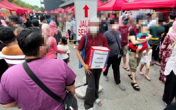 Pengemis (tengah) yang mendakwa dirinya mualaf sebagai modal mengutip derma di bazar Ramadan PKNS.