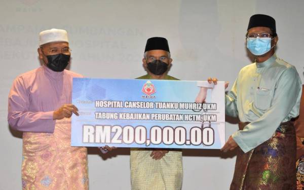 Idris (kiri) menyampaikan replika cek bernilai RM200,000 kepada Pengarah Hospital Canselor Tuanku Muhriz Profesor Datuk Dr Razman Jarmin (kanan) di Hospital Putrajaya, pada Jumaat. Foto Bernama