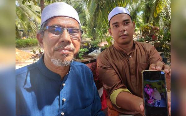 Muhammad Farid (kanan) dan Arbak (kiri) menunjukkan gambar Allahyarhamah Norhamidah.