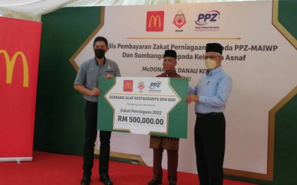 Abdul Hakim (kanan) menerima bayaran zakat McDonald's Malaysia diwakili Azhar (kiri) sambil disaksikan Mohd Nizam pada Jumaat.