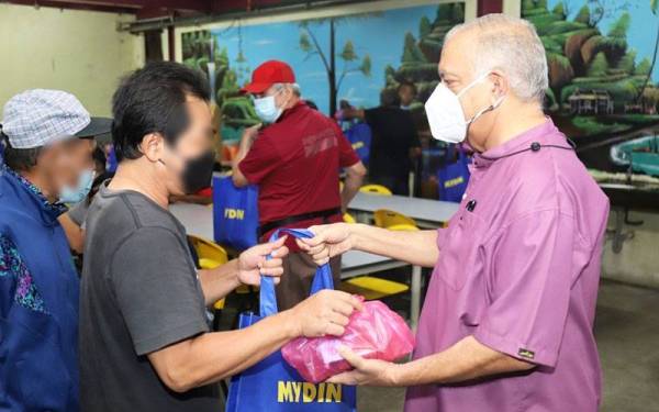 Ameer (kanan) menyampaikan pek makanan kepada salah seorang gelandangan pada Program Sahur Mydin Prihatin telah diadakan di Pusat Transit Gelandangan Kuala Lumpur.