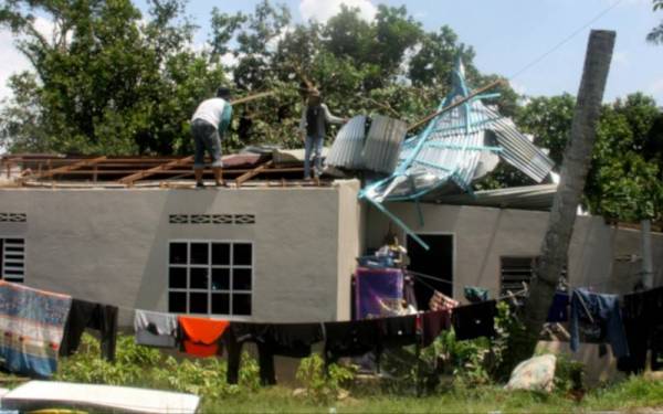 Beberapa pekerja sedang membersihkan atap rumah penduduk, Faridzul Rohaizak Sulaiman yang mengalami kerosakan susulan kejadian ribut di Kampung Garok, Sungai Bayur. - Foto Bernama