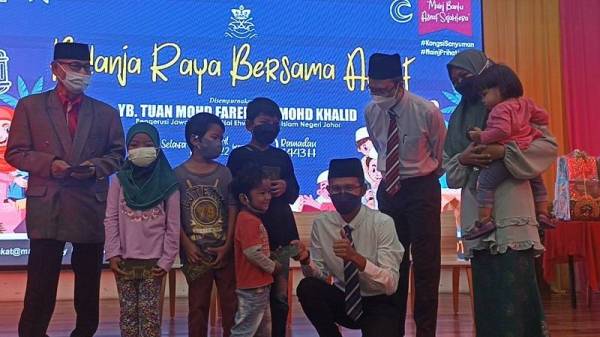 Mohd Fared (tiga dari kiri) bertanyakan sesuatu kepada salah seorang anak Zalinda (kiri) pada program Belanja Raya Bersama Asnaf di Mydin Mall Mutiara Rini.