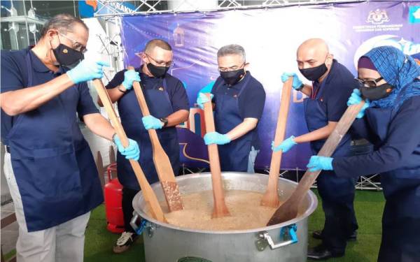 Mohammad Hanis (tengah) bersama Jawatankuasa Pengurusan Bank Rakyat mengacau bubur lambuk sebagai gimik pengagihan bubur lambuk itu pada program 'Rindunya Ramadan' 2022 di MKBR, Kuala Lumpur pada Rabu.