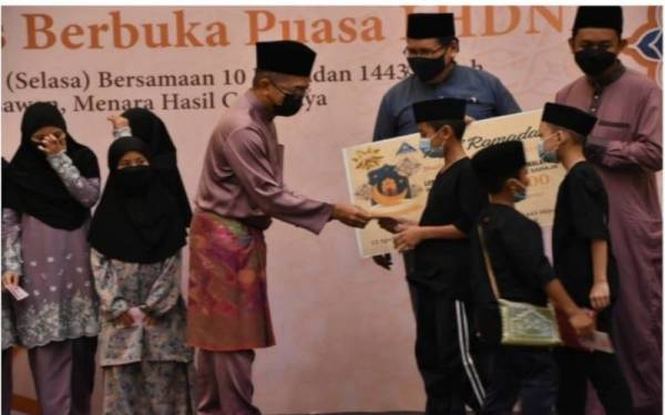 Yamani Hafez (tengah) menyaksikan penyerahan sumbangan duit raya daripada Mohd Nizom kepada anak-anak yatim.