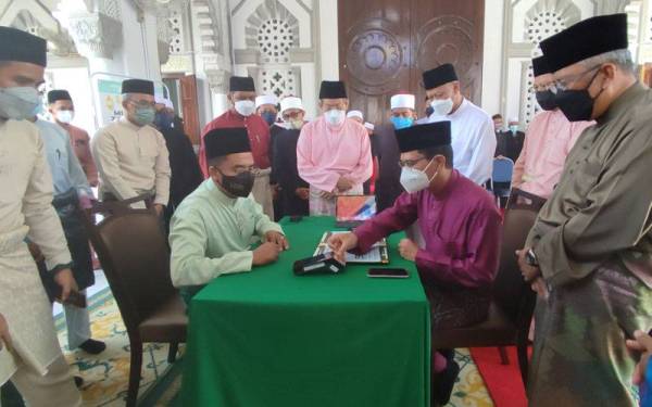 Tengku Sarafudin (duduk kanan) berkenan menunaikan zakat fitrah kepada Zakaria (duduk kiri) di Masjid Zahir, Alor Setar pada Jumaat.