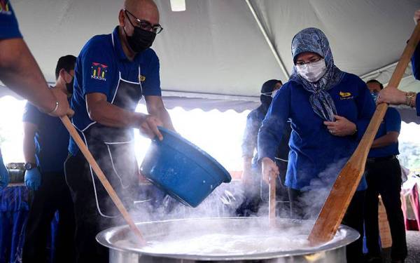 Tunku Azizah (kanan) berkenan memasak bubur lambuk sempena Program Bubur Lambuk bersama KEKSIN di Istana Negara pada Sabtu. - Foto Bernama