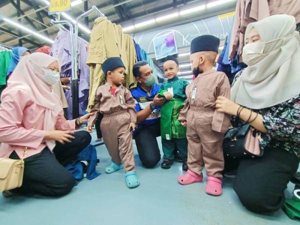 Ahmad Saidi (tiga dari kiri) membantu tiga kanak-kanak memilih baju raya sempena Program Cahaya Aidilfitri GPMS Perak di Pasaraya Mydin di Gopeng pada Sabtu.