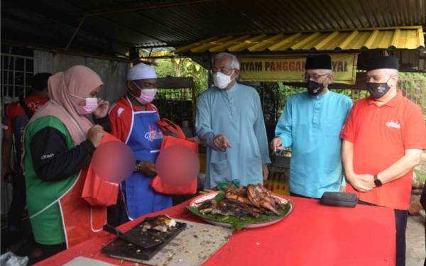 Mahdzir (tengah) beramah mesra dengan peniaga ayam di bazar Ramadan pada Program Semarak Kasih Ramadan Kementerian Pembangunan Luar Bandar (KPLB) di Felda Lubuk Merbau, pada Sabtu.