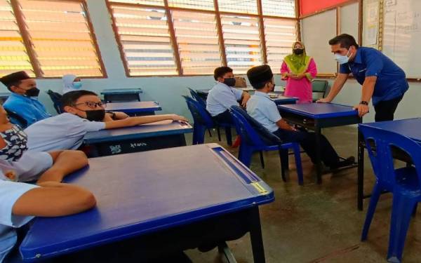 Mohd Radzi (kanan) beramah mesra dengan murid di SK Seri Ketereh semasa meninjau pengoperasian sekolah tanpa menggunakan sistem penggiliran pada Ahad.