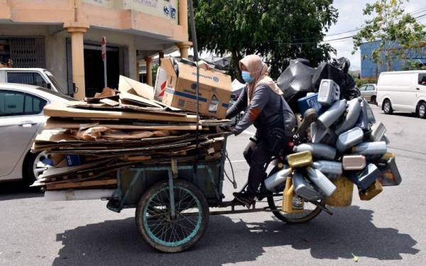 Umi Nur Faizah mengayuh kereta sorongnya dipenuhi barangan terpakai yang dikutip untuk dijual ke kedai barangan terpakai ketika tinjauan Bernama di Taman Perindustrian Malim baru-baru ini.  - Foto Bernama