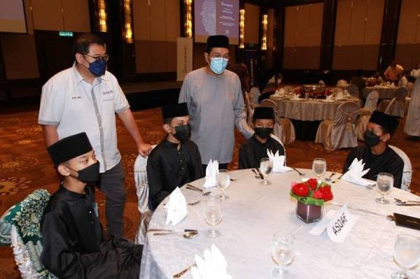 Safian (berdiri (kanan) beramah mesra dengan anak-anak asnaf Asrama Darul Falah (ASDAF) selepas menyampaikan sumbangan Hari Raya yang diadakan di Hotel Intercontinental, Kuala Lumpur pada Isnin. -Foto Rosli Talib