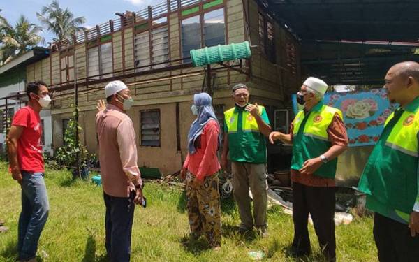 Maisarah (tiga dari kiri) menunjukkan keadaan bumbung rumahnya yang diterbangkan angin kepada Awang Hashim, Ahli Dewan Undangan Negeri (ADUN) Tokai, Datuk Dr Mohd Hayati Othman dan ADUN Pedu,Mohd Radzi Md Amin di Kampung Majapahit pada Selasa.