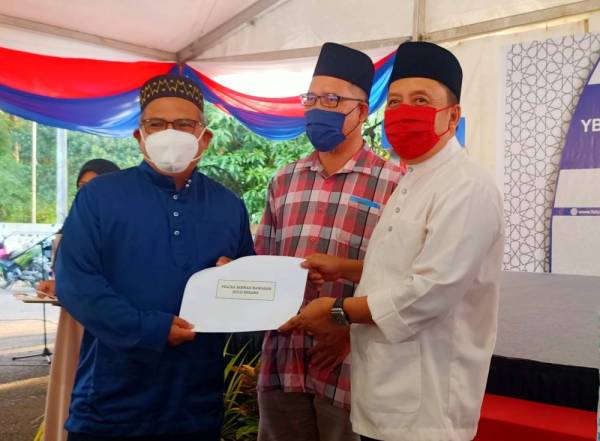 Ahmad Jazlan (kanan) menyampaikan sumbangan semasa Majlis iftar Ramadan Felcra Berhad di Pusat Transformasi Ilmu, Bukit Tiu, Machang pada Selasa.